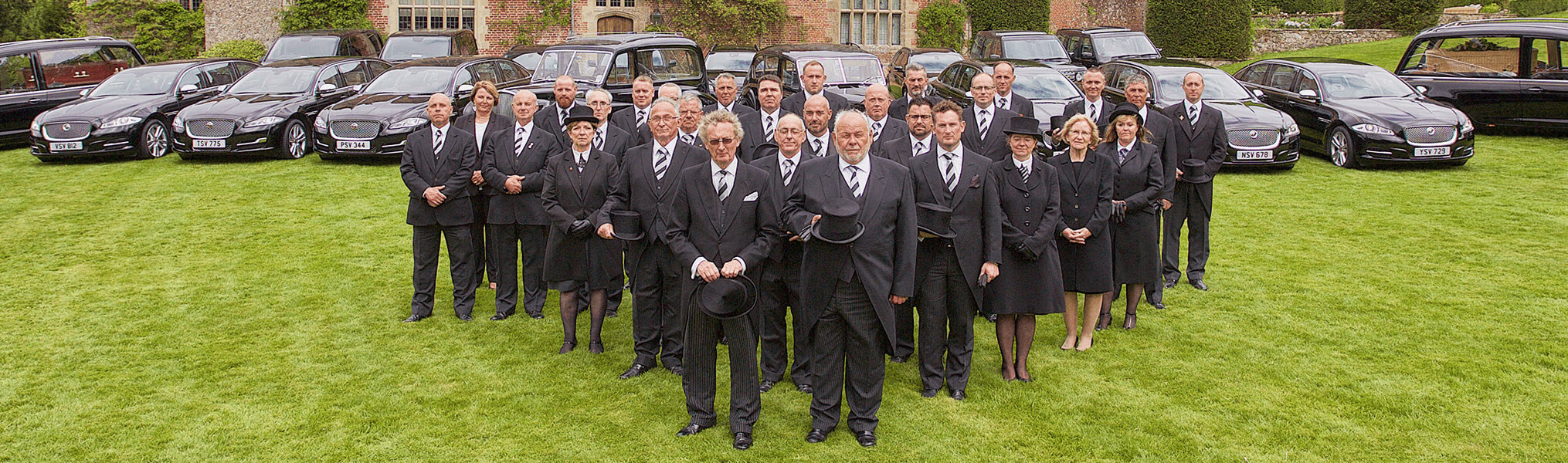 Funeral Directors standing in a group Infront of hearses